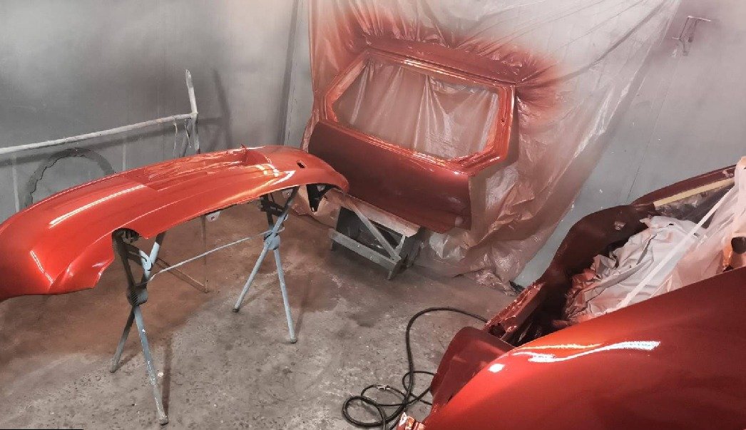 Paragolpes, puerta y capot recién pintados en color cobre metalizado, en la cabina de pintura de Quebecar